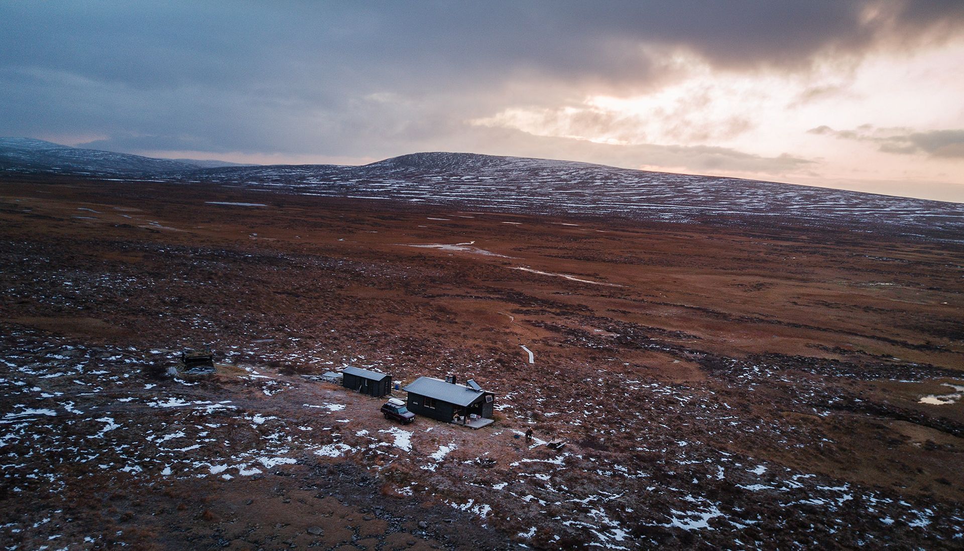 An aerial view of a snowy field with a mountain in the background