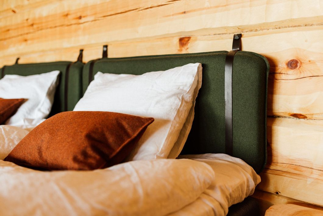 A bed with a green headboard and brown pillows in a wooden room.