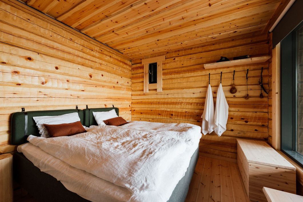 A bedroom in a log cabin with a bed and a window.
