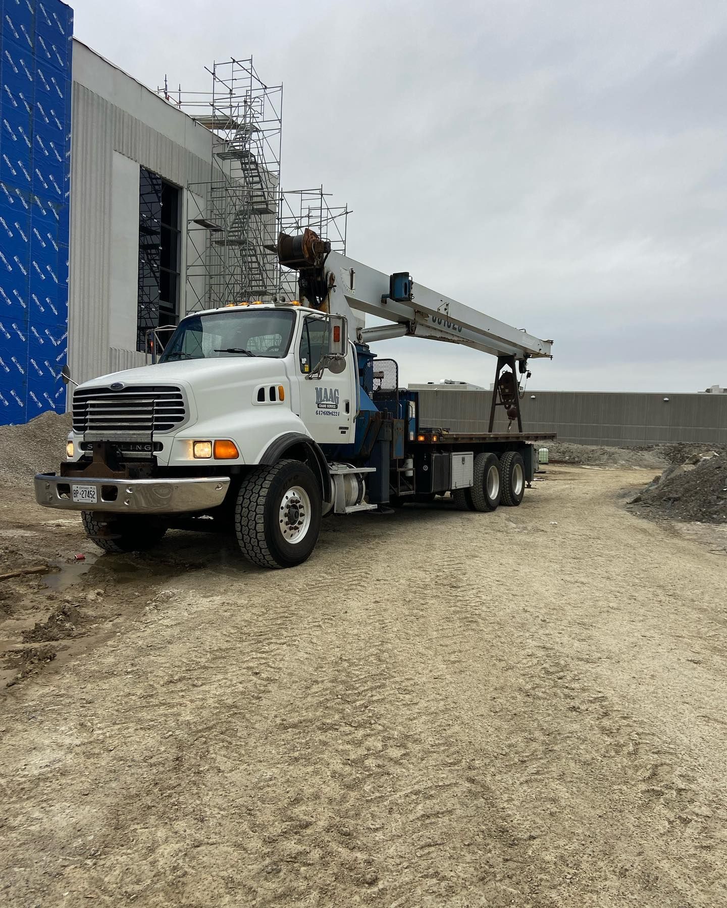 Open truck interior filled with stacked tires, tire changing machine, tools, and a ladder, outdoors.