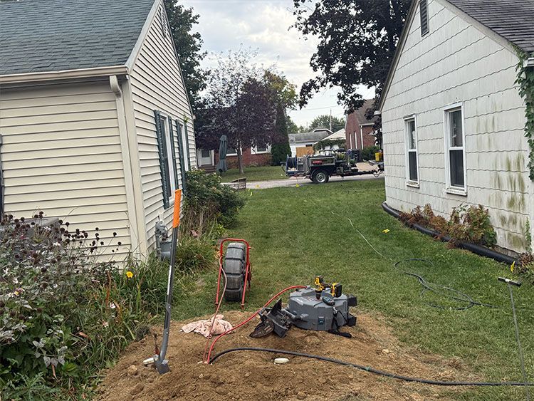 Equipment near houses; plumbing or utility work in progress, outdoor setting.