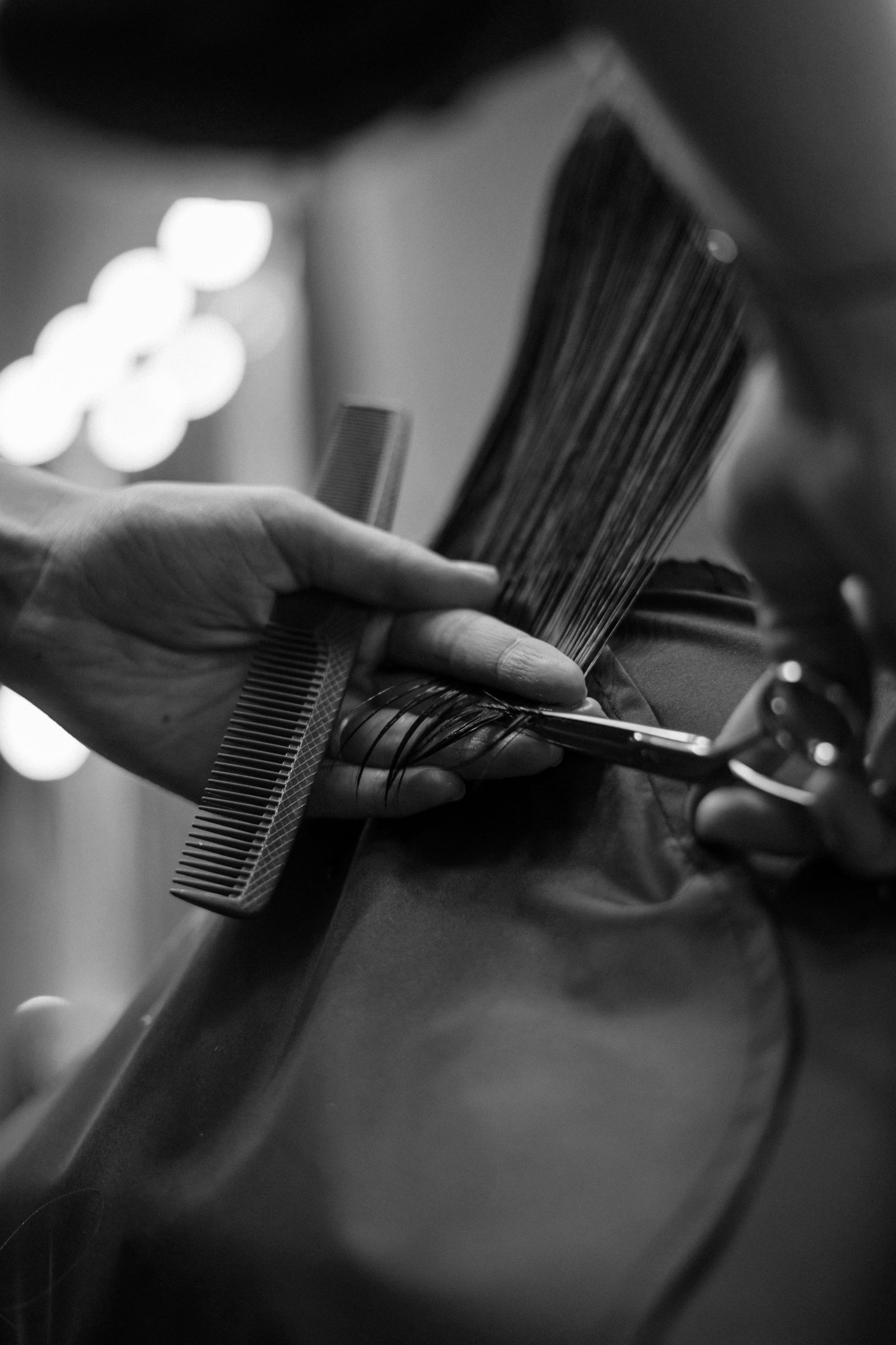 Hairdresser cutting hair with scissors and comb.