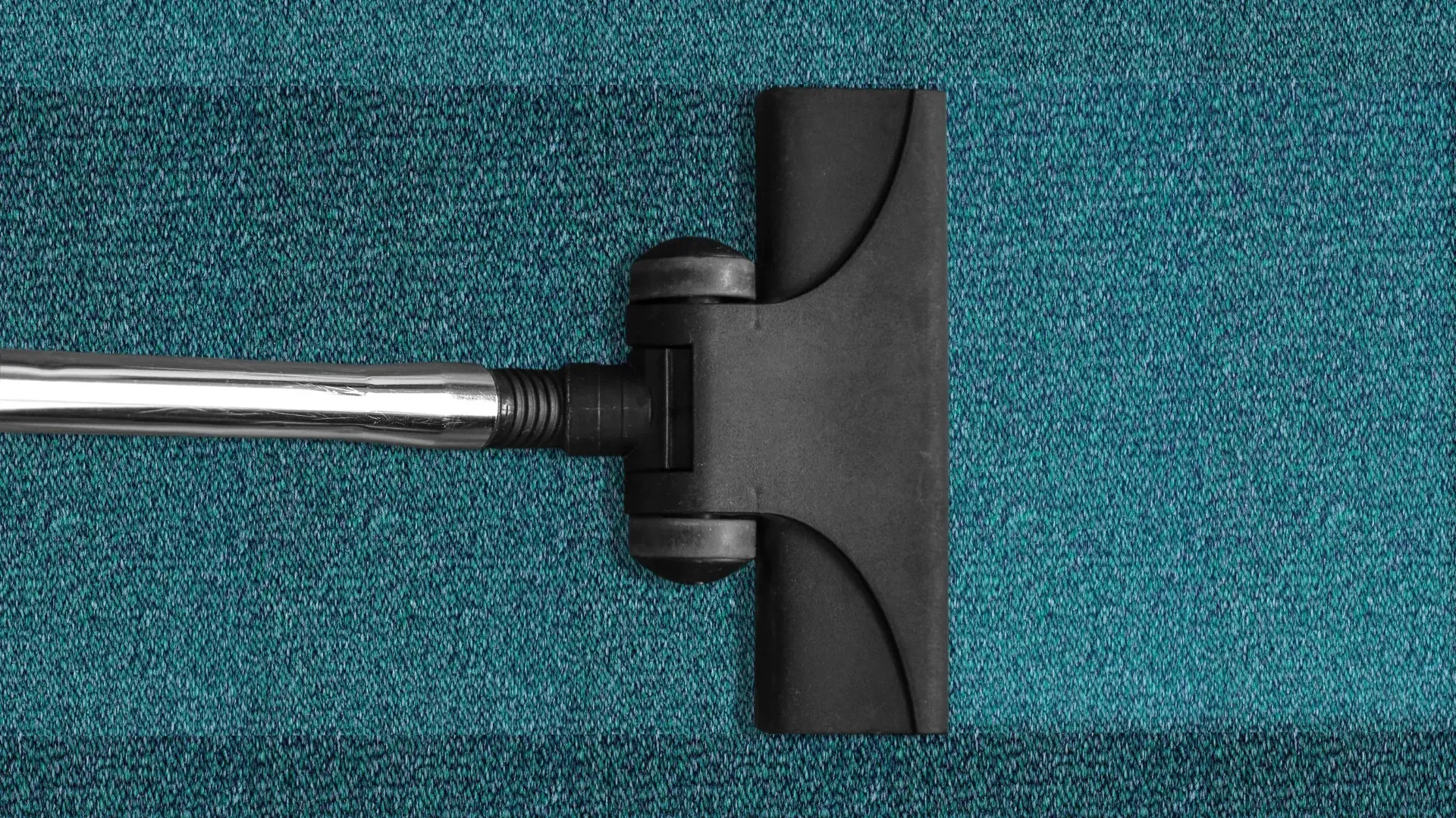 A vacuum cleaner is cleaning a blue carpet.