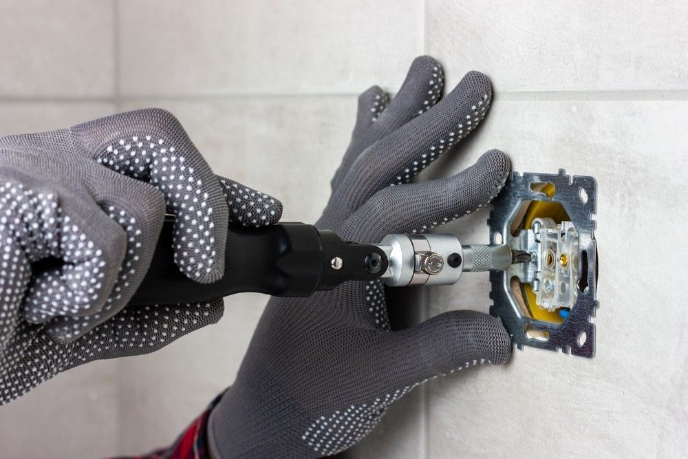 A Person is Installing a Light Switch on a Wall — A J Wilcox Air & Electrical in Banora Point, NSW