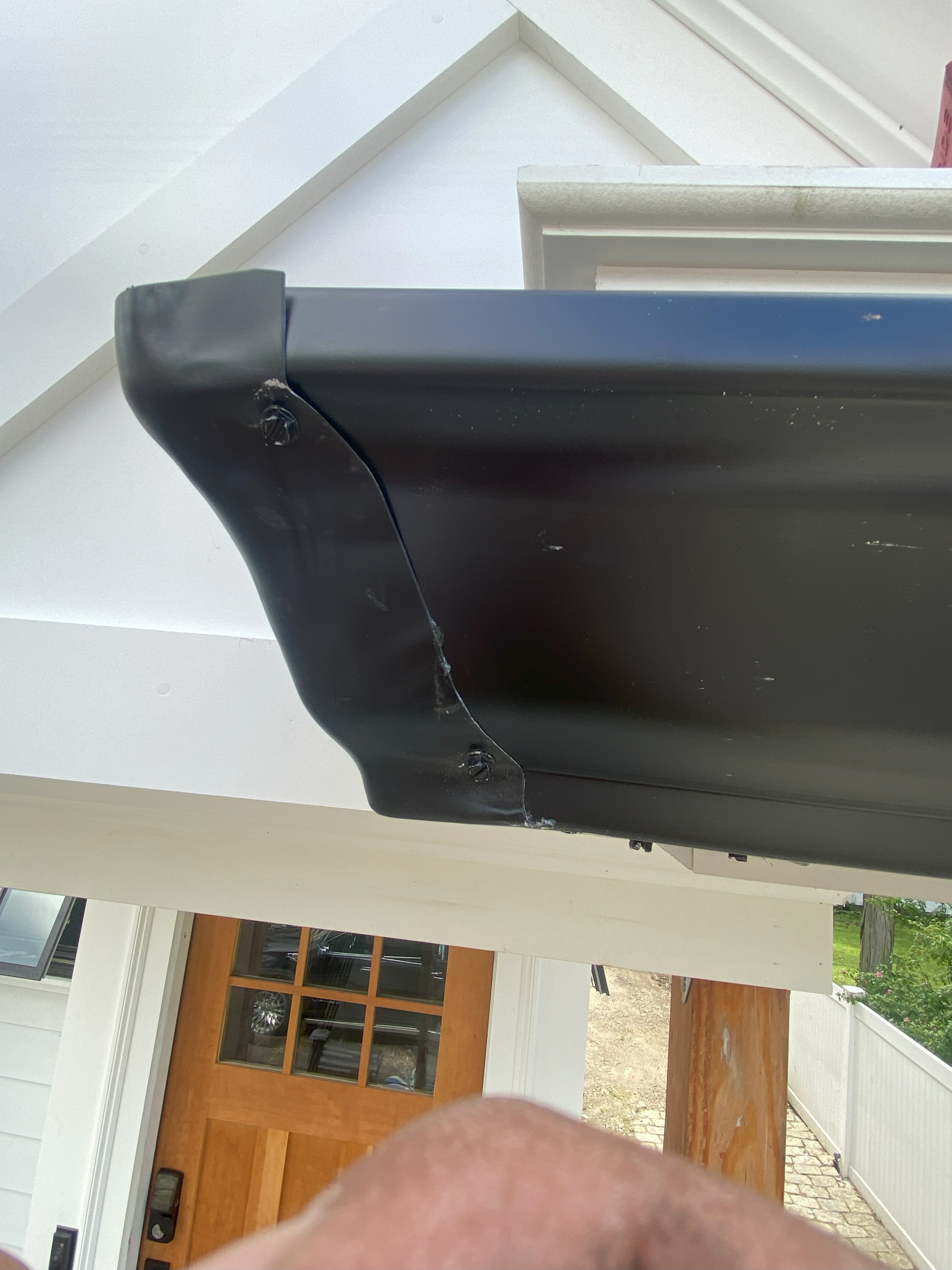 A person is looking down at a black gutter on a house.