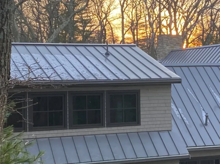 A house with a metal roof and a sunset in the background
