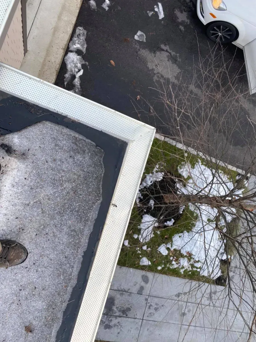 An aerial view of a gutter with snow on it and a car parked in the background.