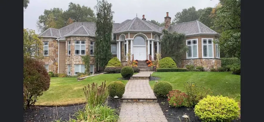 A large house with a lush green lawn and a walkway leading to it.