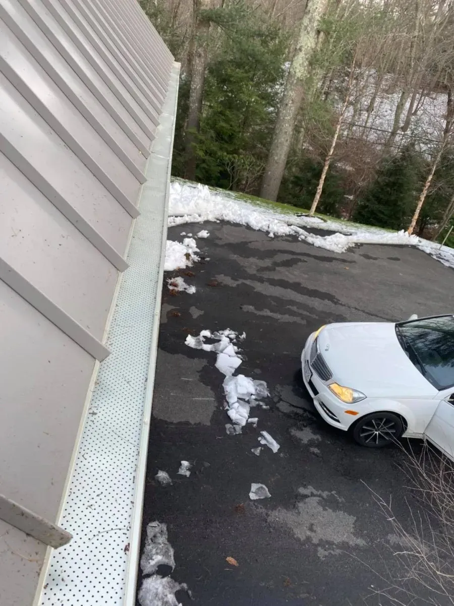 A white car is parked in a parking lot next to a gutter.