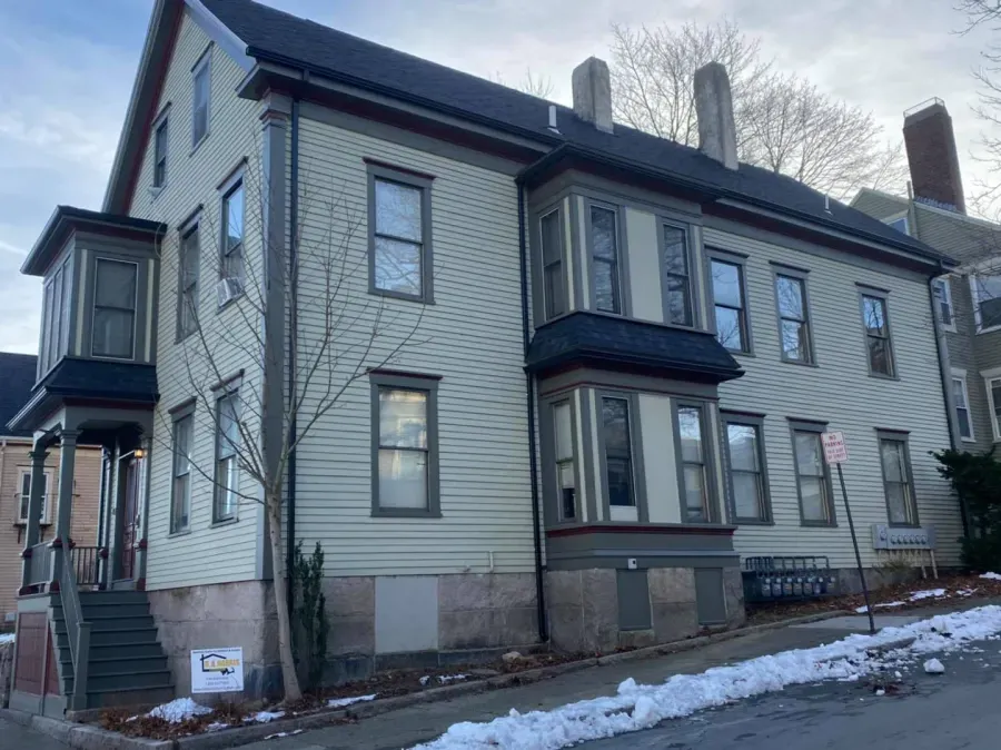 A large house with a lot of windows is sitting on a snowy street.