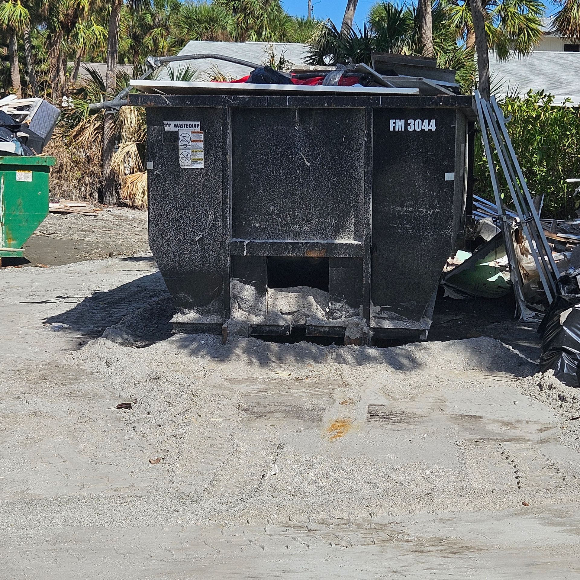 Black Waste Haul dumpster with white and red company sign on a gravel lot