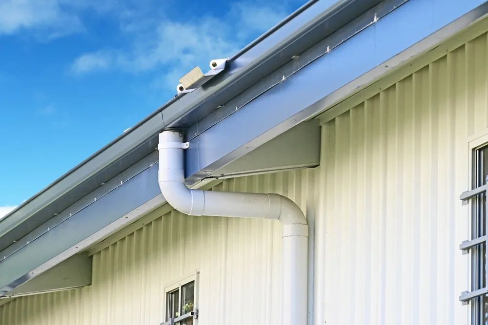 A white pipe is attached to the side of a building