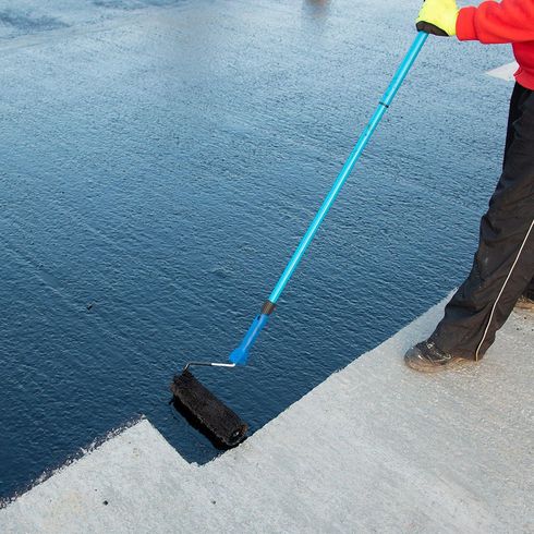 A person is painting a concrete surface with a roller
