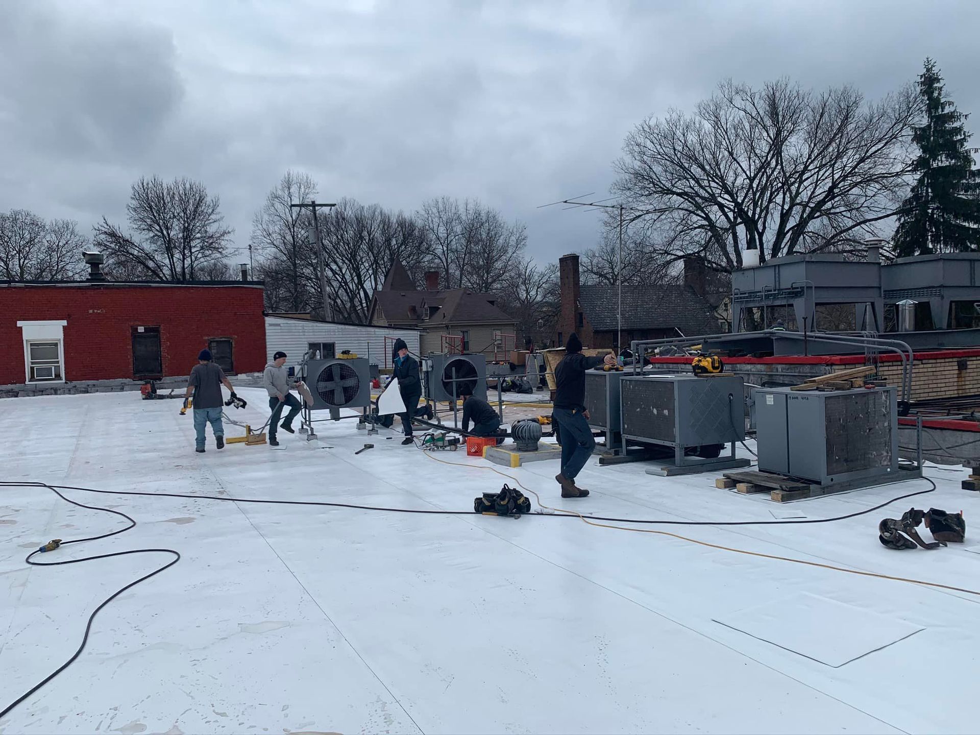 A group of people are working on a snow covered roof.