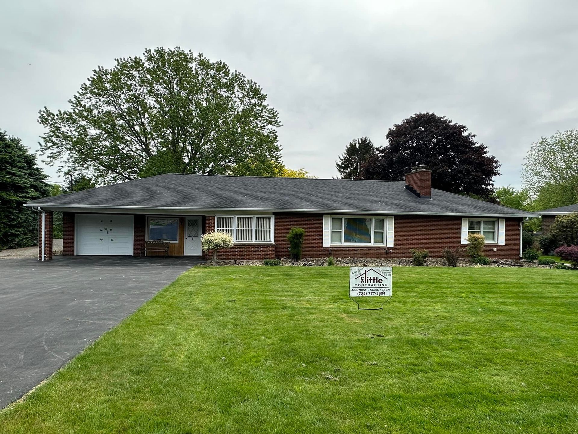 A brick house with a black roof is for sale