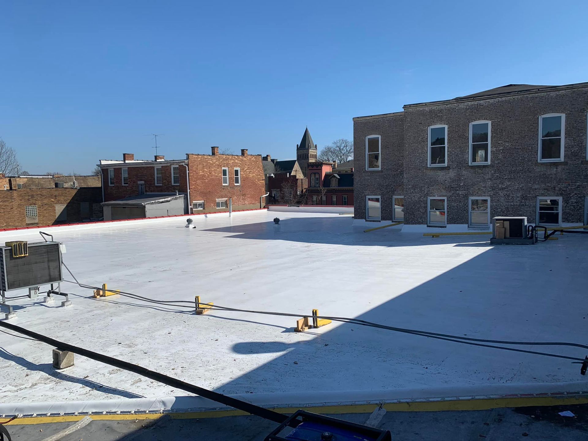 A snowy roof with a brick building in the background
