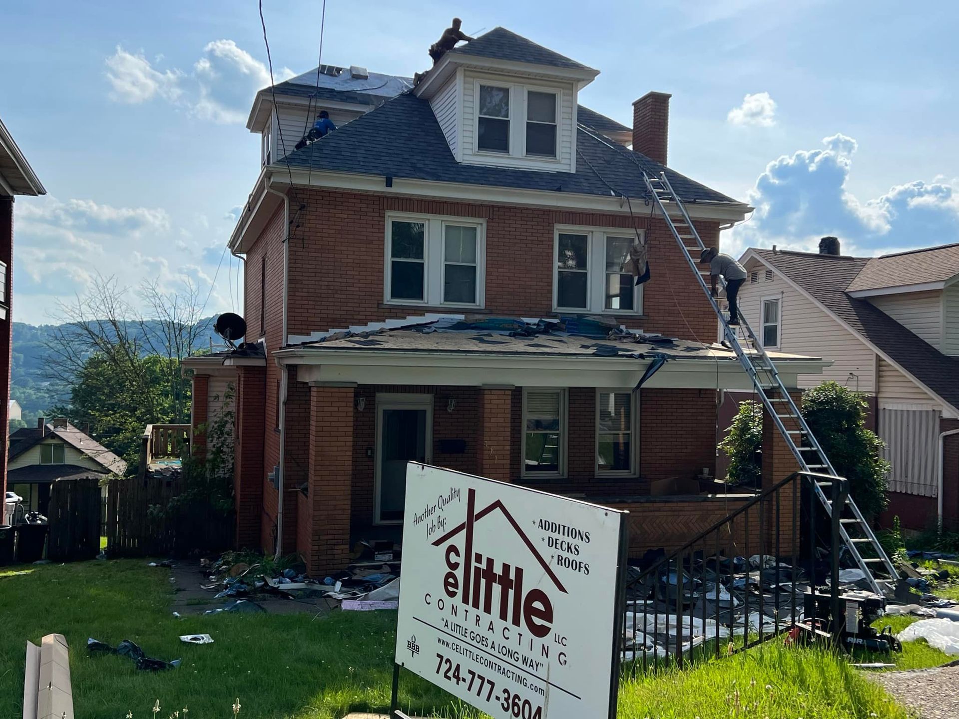 A brick house is being remodeled with a sign in front of it.
