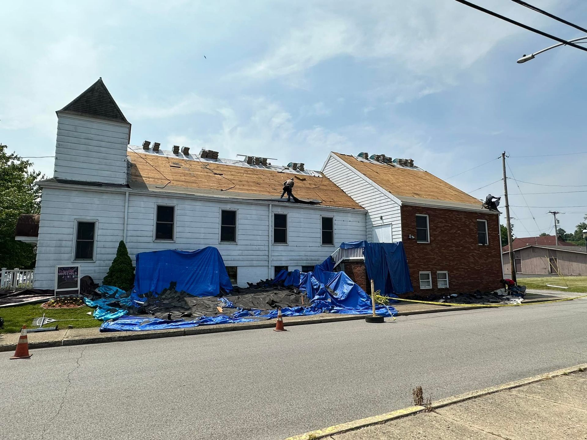 A large white building with a roof that is being repaired.