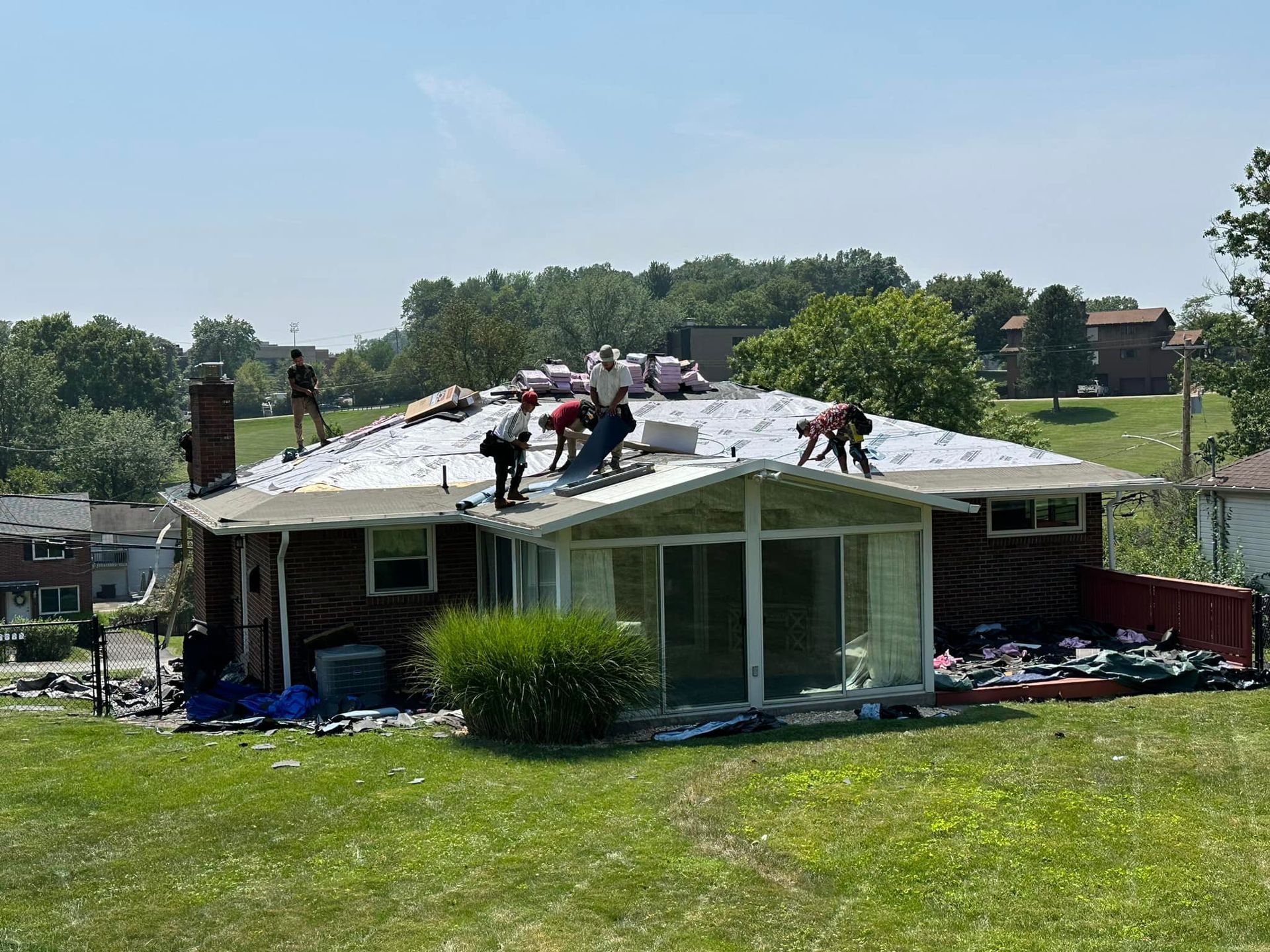 A group of people are working on the roof of a house.