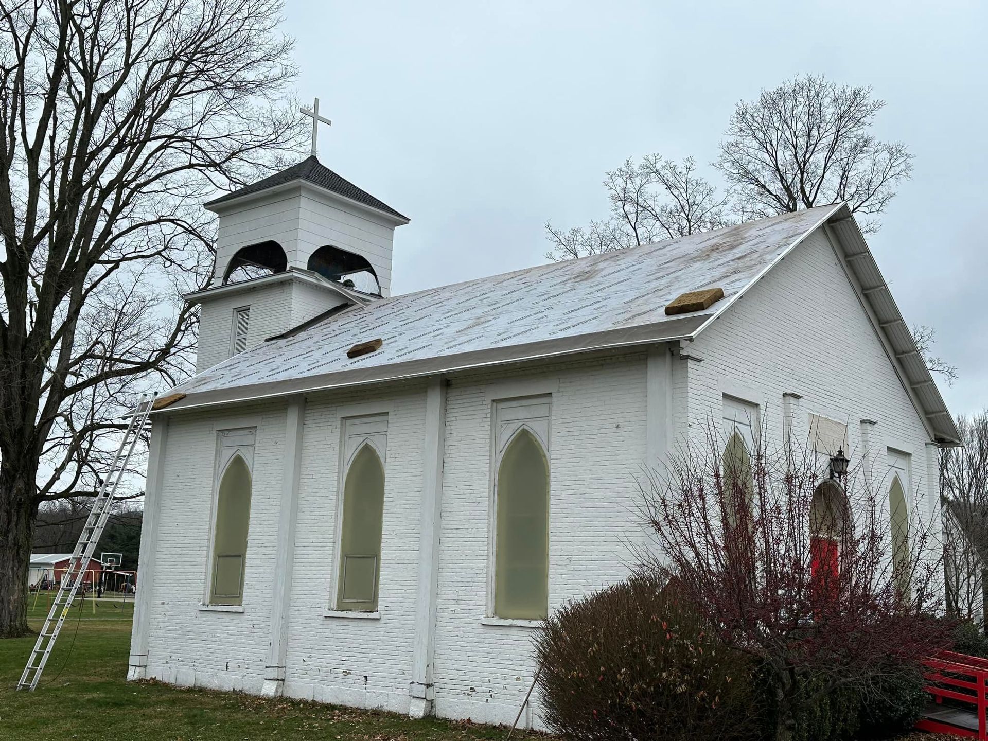 A small white church with a ladder in front of it.