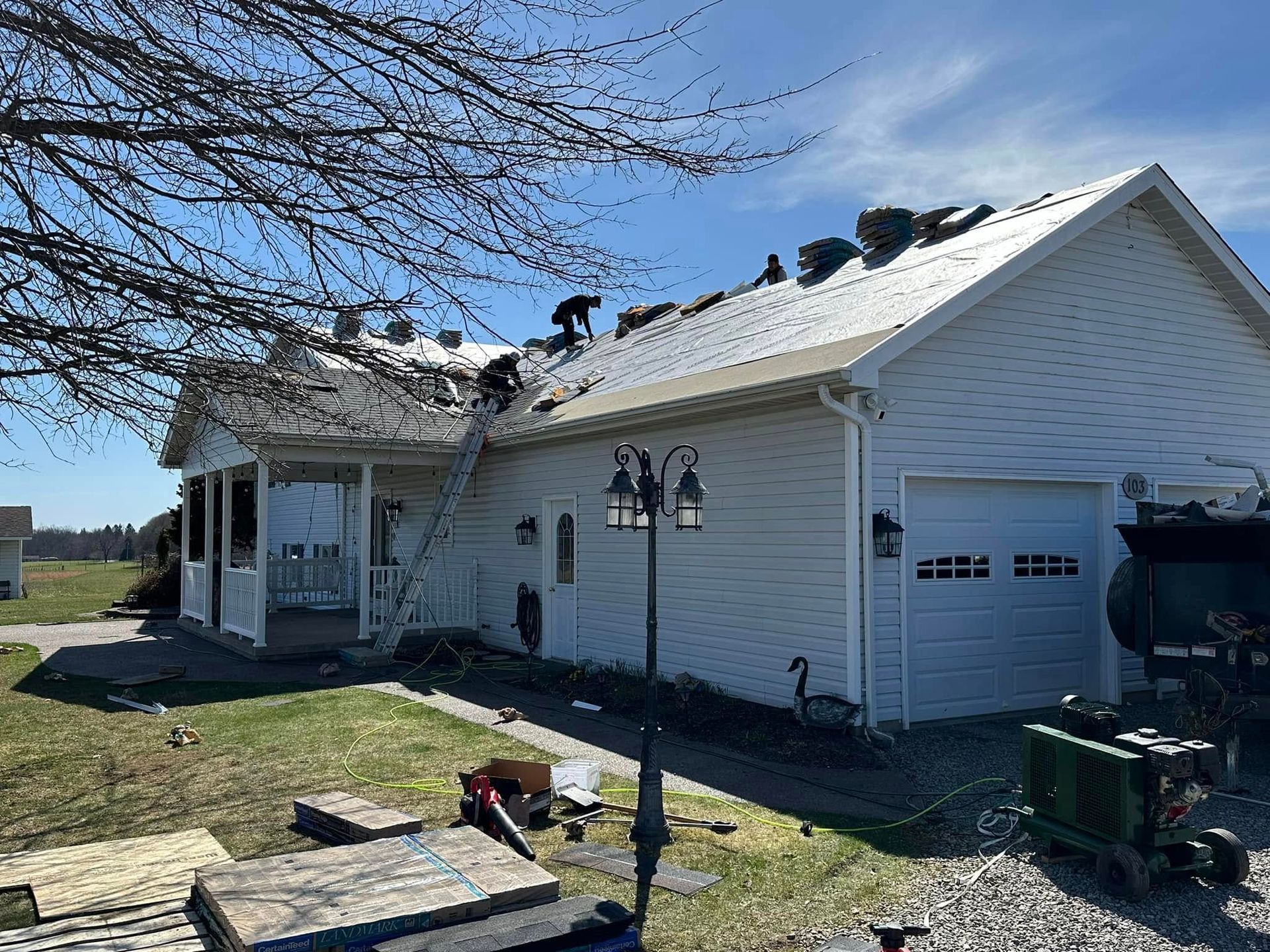 A white house with a roof that is being repaired.