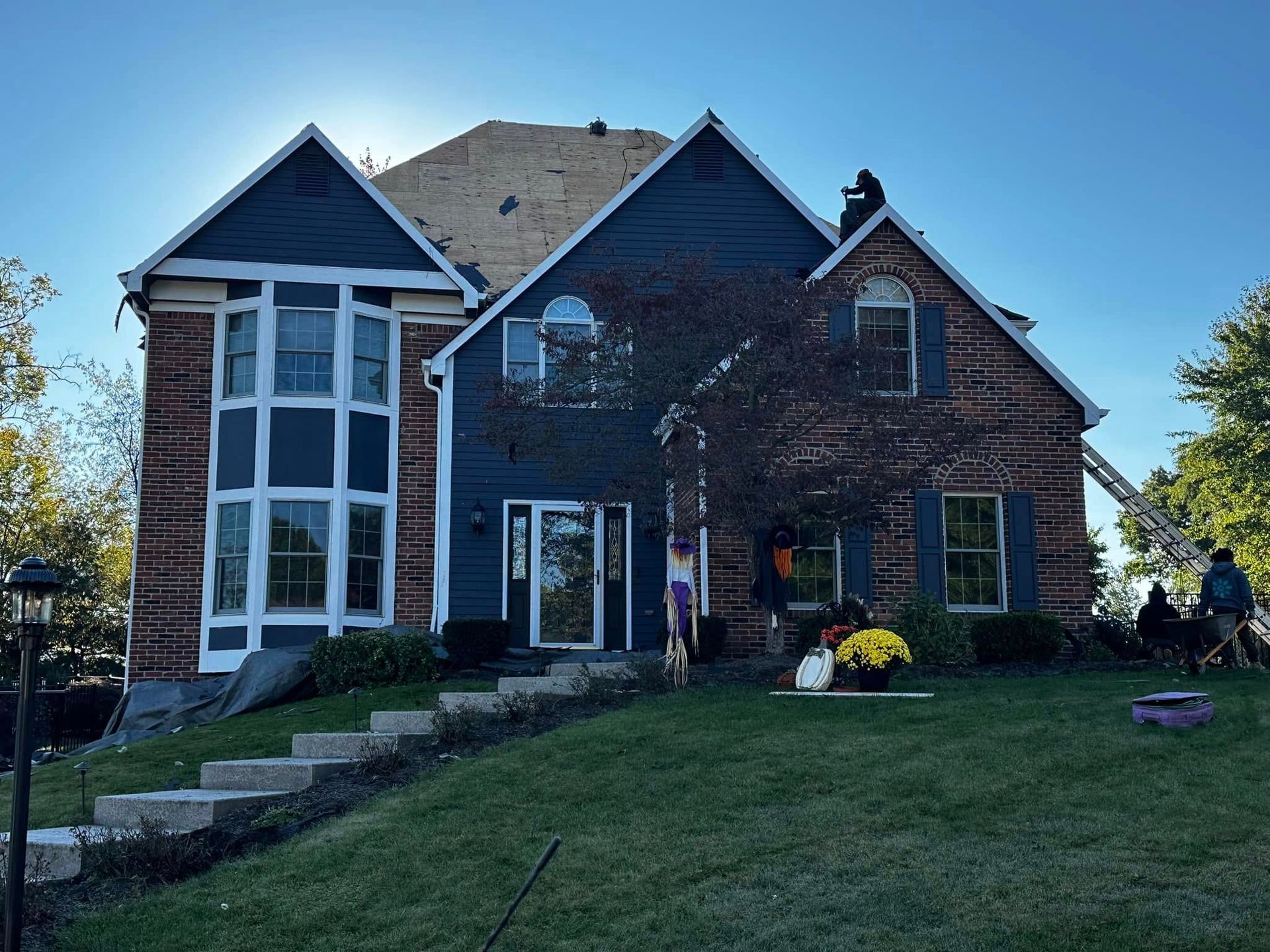 A large brick house with a blue siding is being remodeled.
