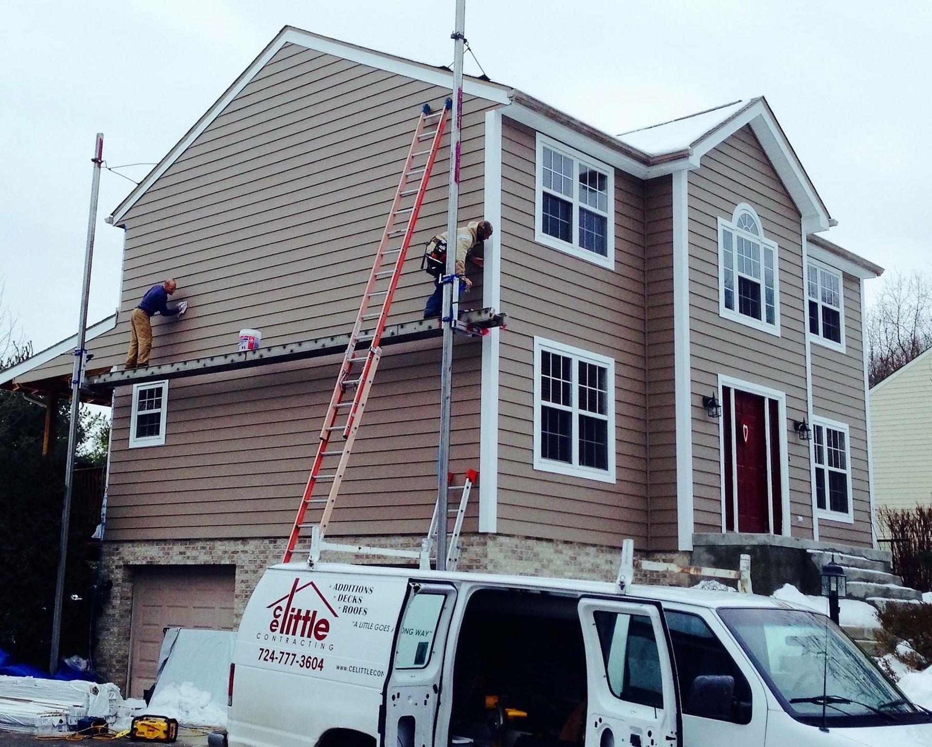 A white van is parked in front of a house that is being painted