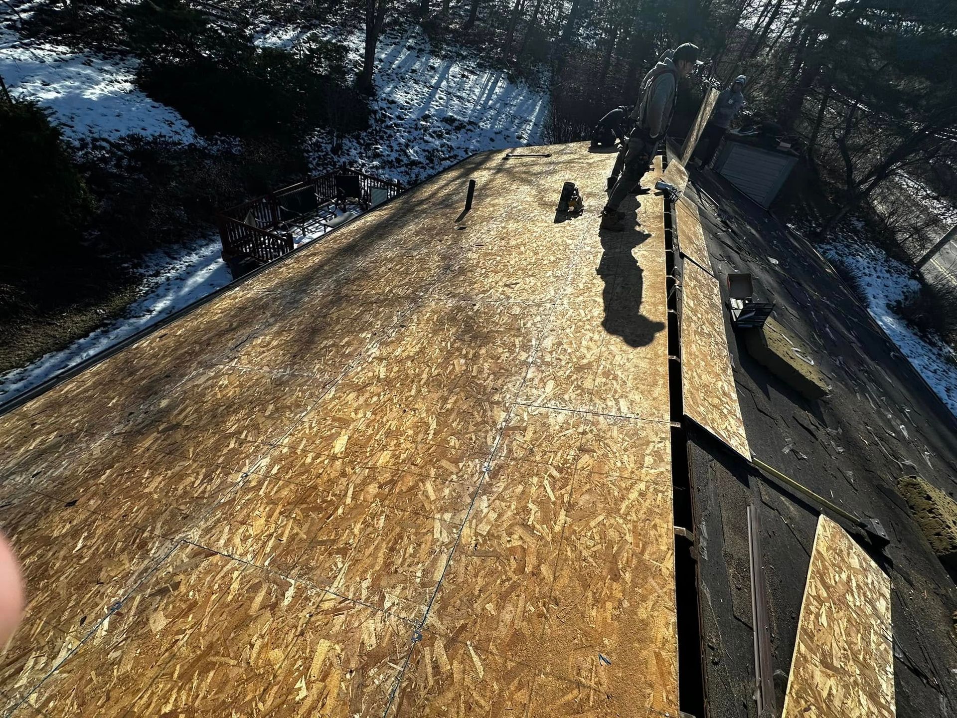 A person is standing on top of a wooden roof.