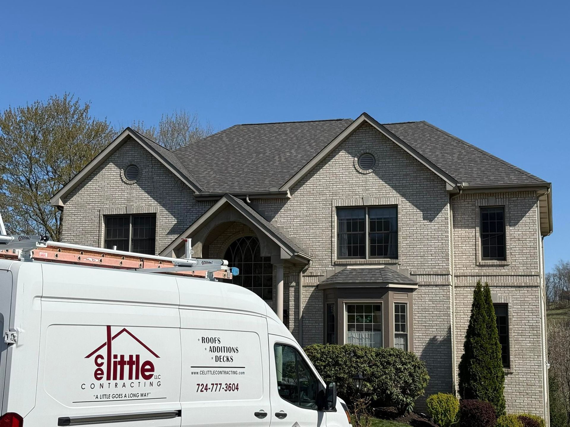 A white van is parked in front of a large brick house.