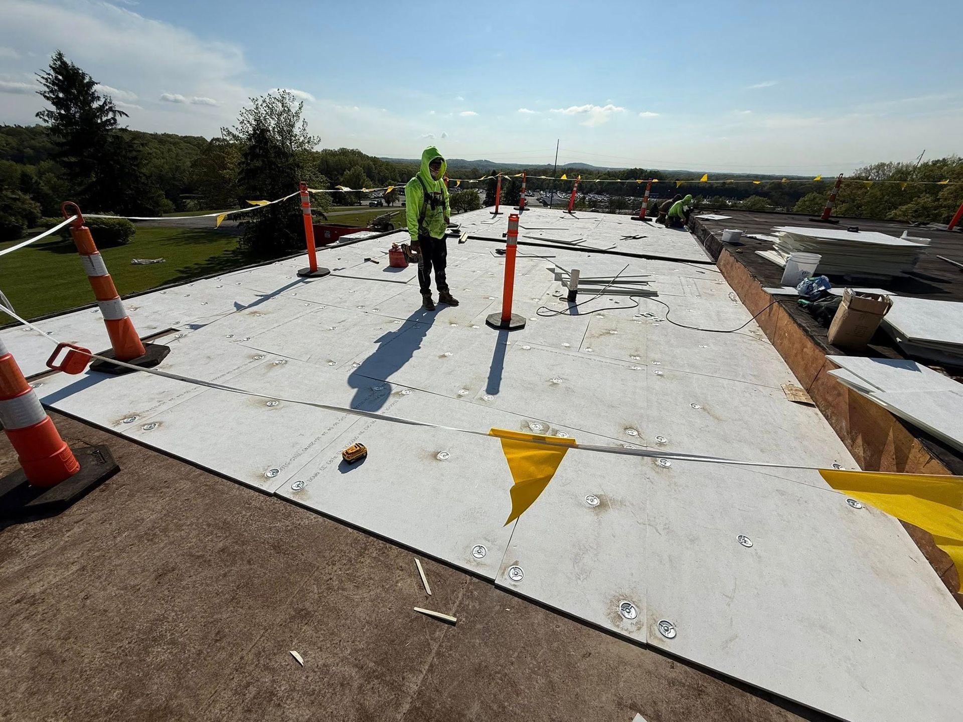 A man is standing on top of a white roof.