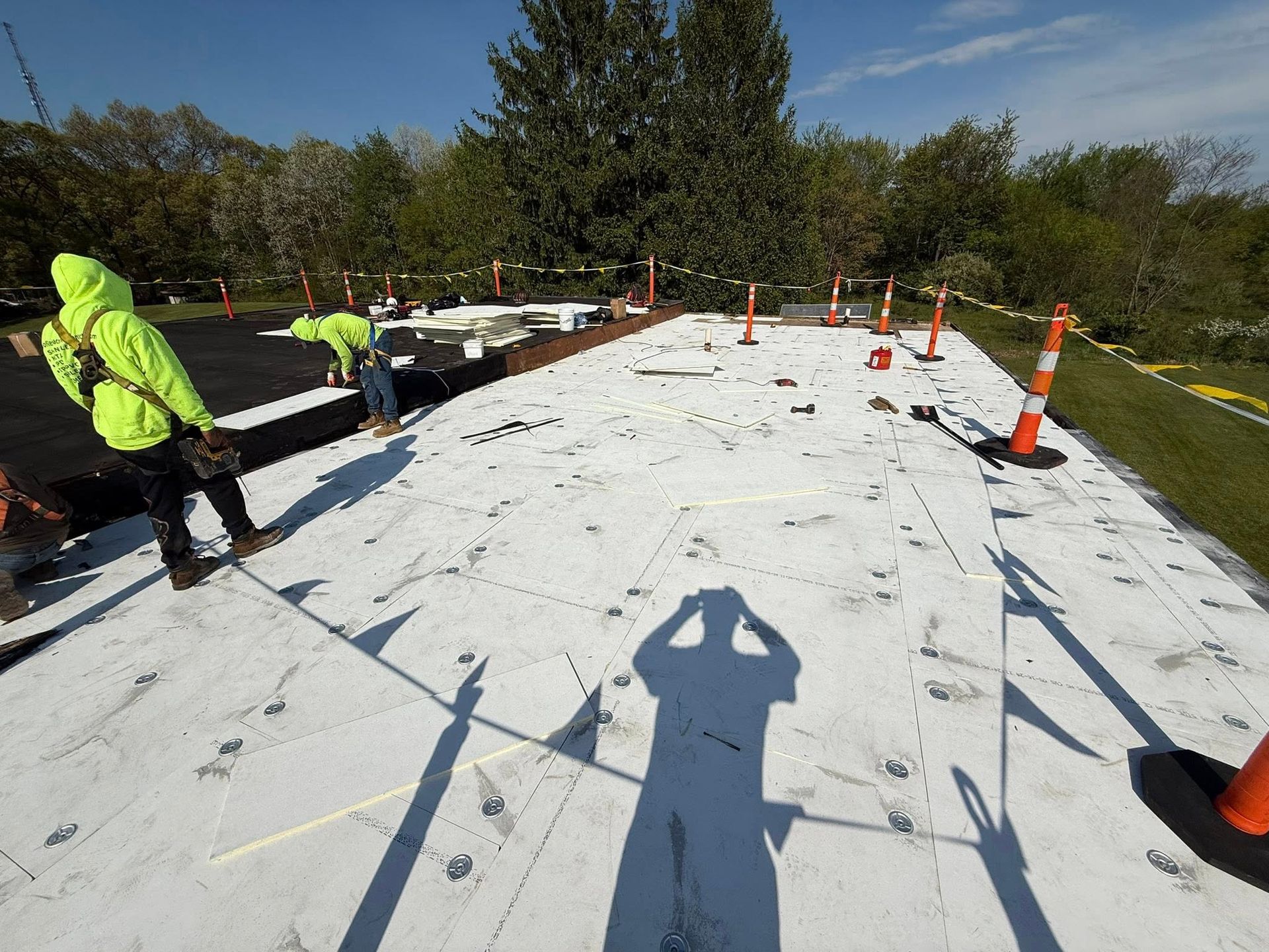 A group of construction workers are working on a white roof.