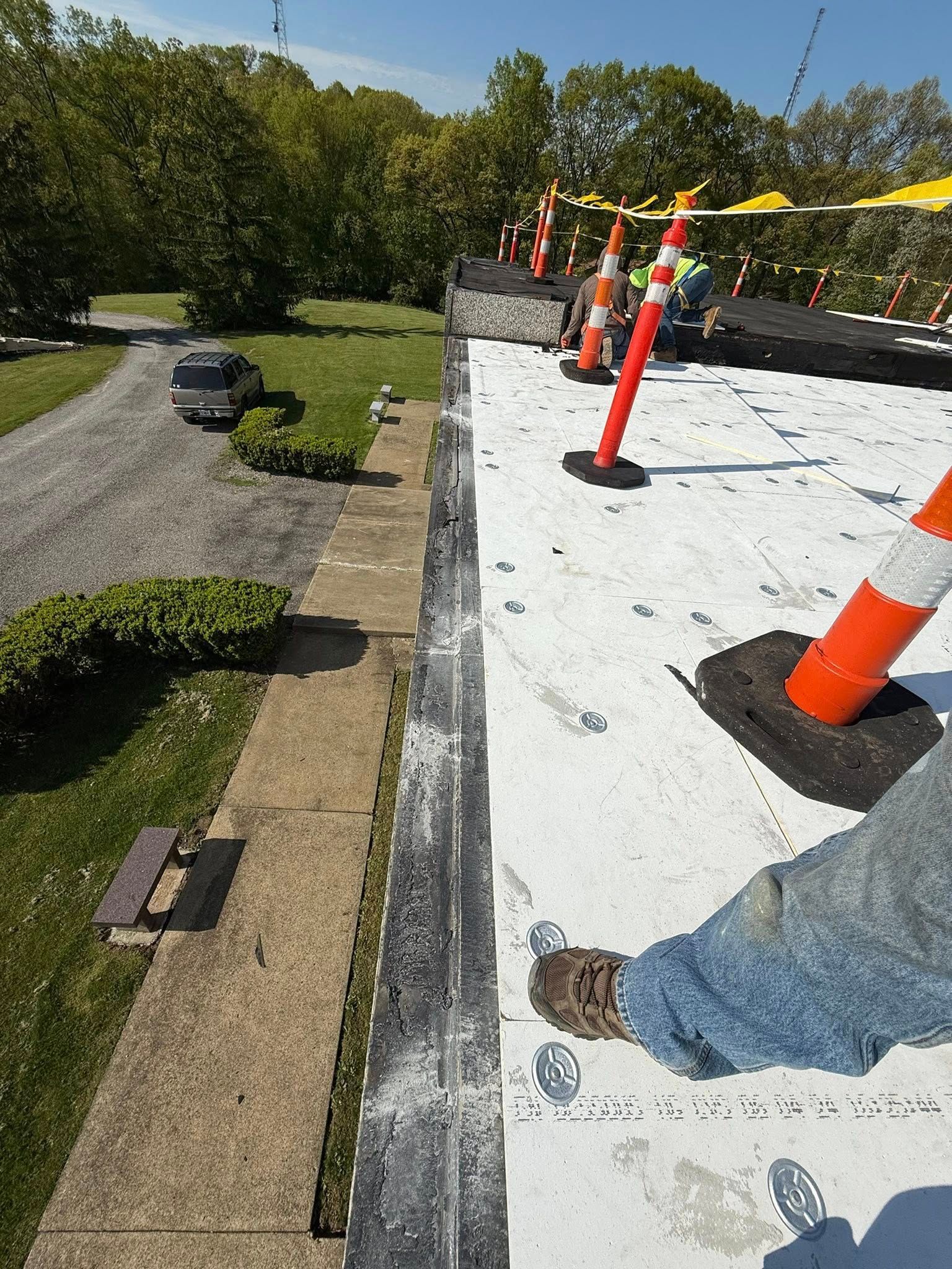 A person is standing on top of a white roof.