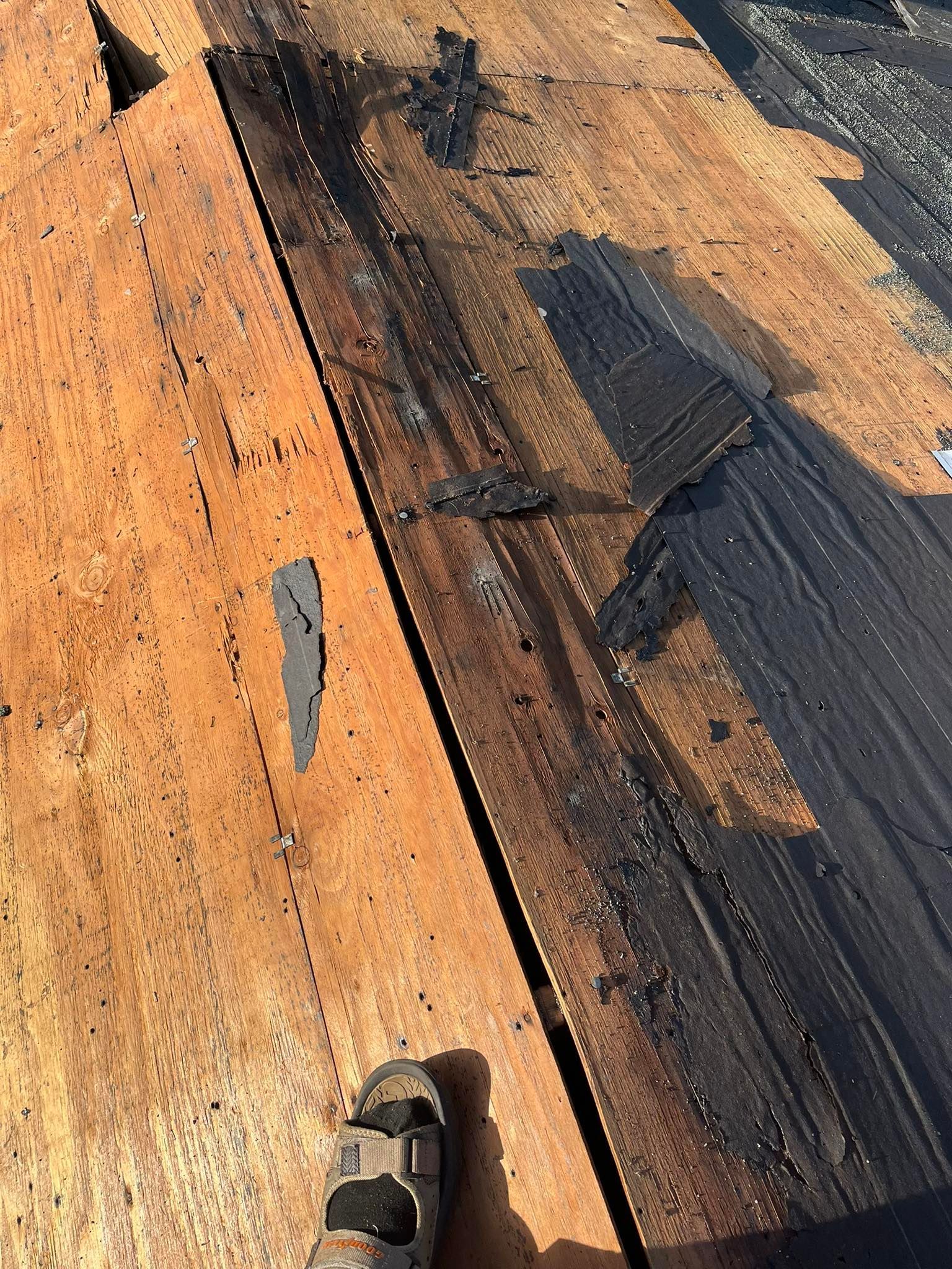 A person is standing on a wooden table with a pair of sandals on it.