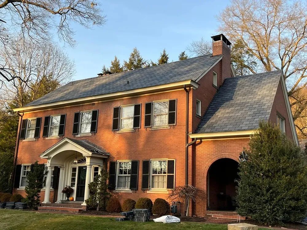 A large brick house with a gray roof and black shutters.