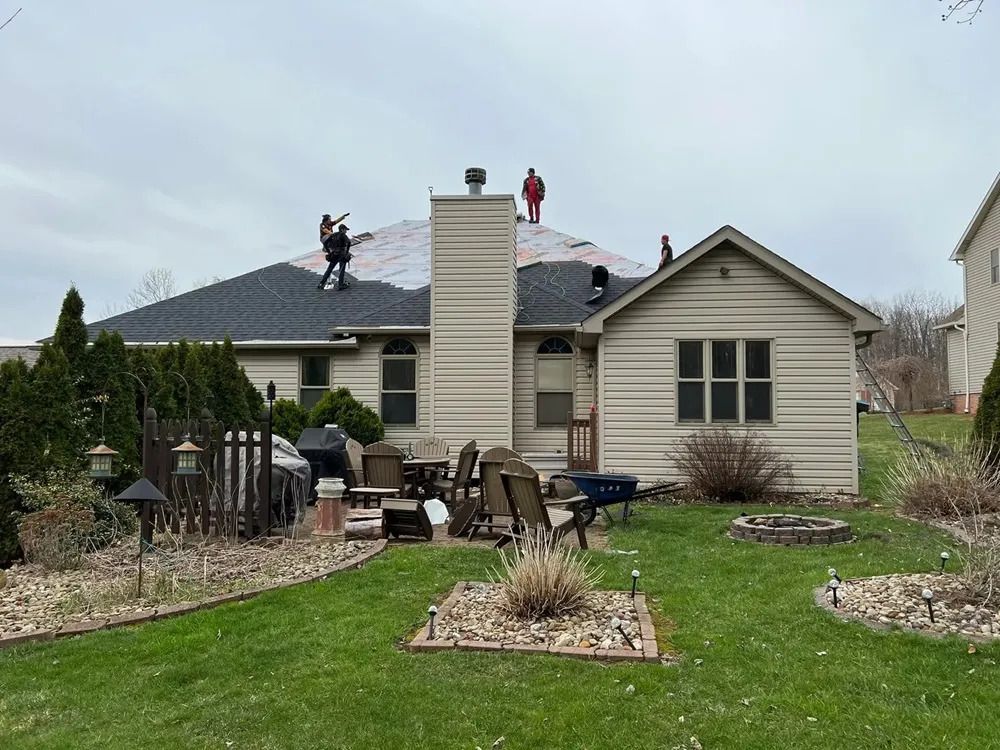 Two men are working on the roof of a house.