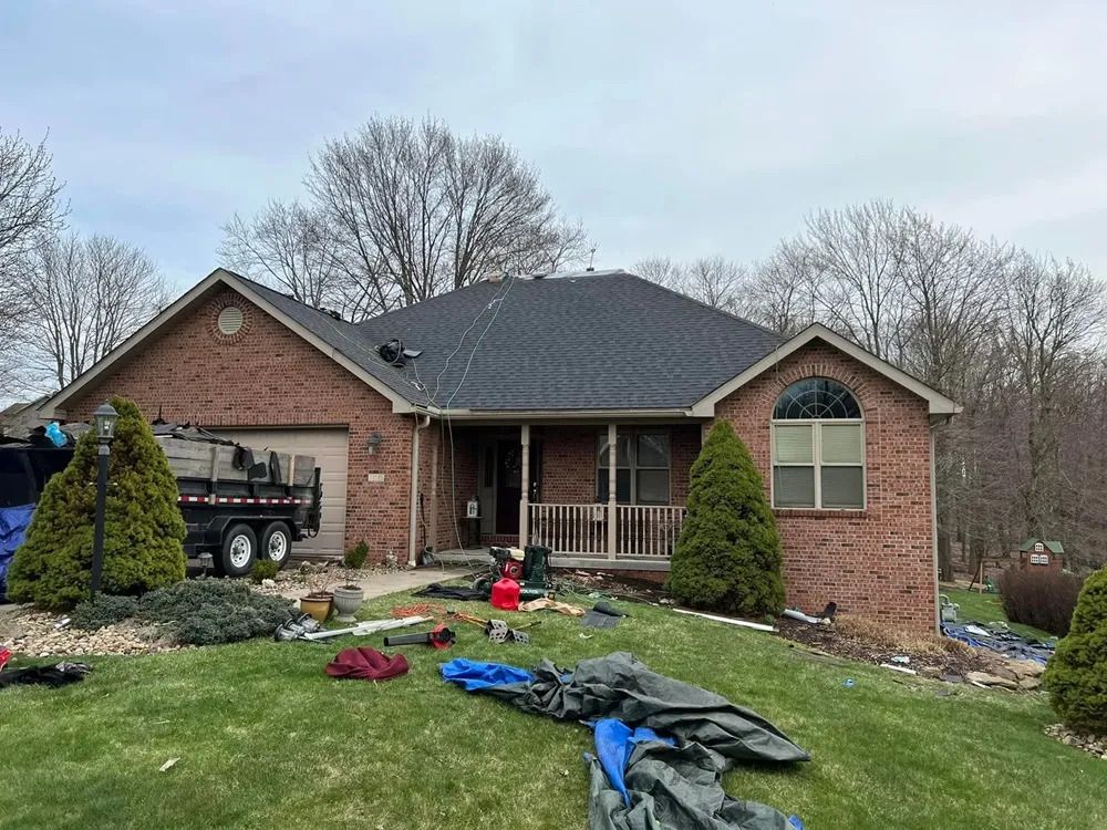 A brick house with a black roof is being remodeled.