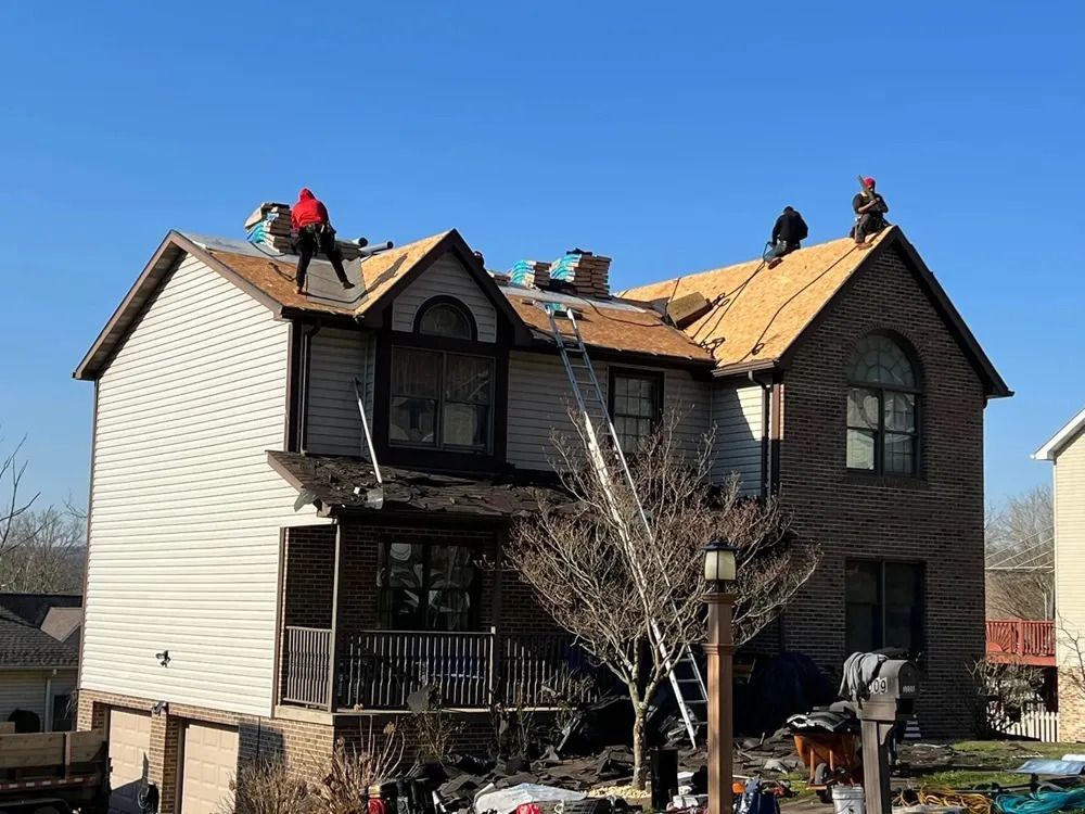 A group of people are working on the roof of a house.