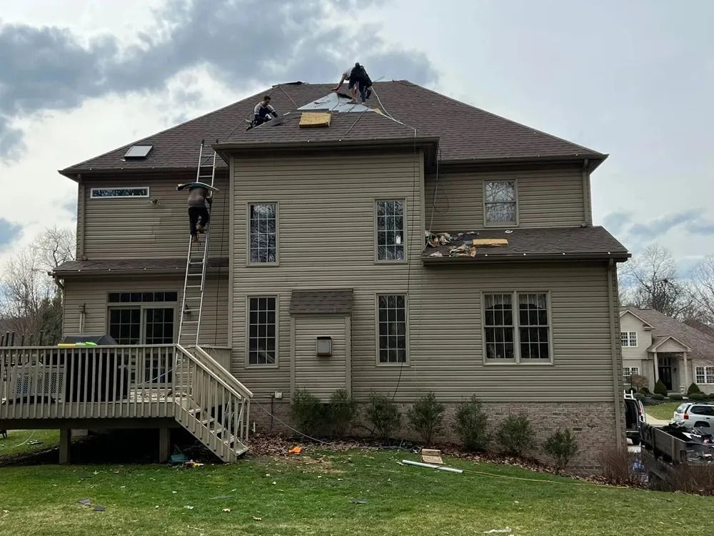 Two men are working on the roof of a large house.