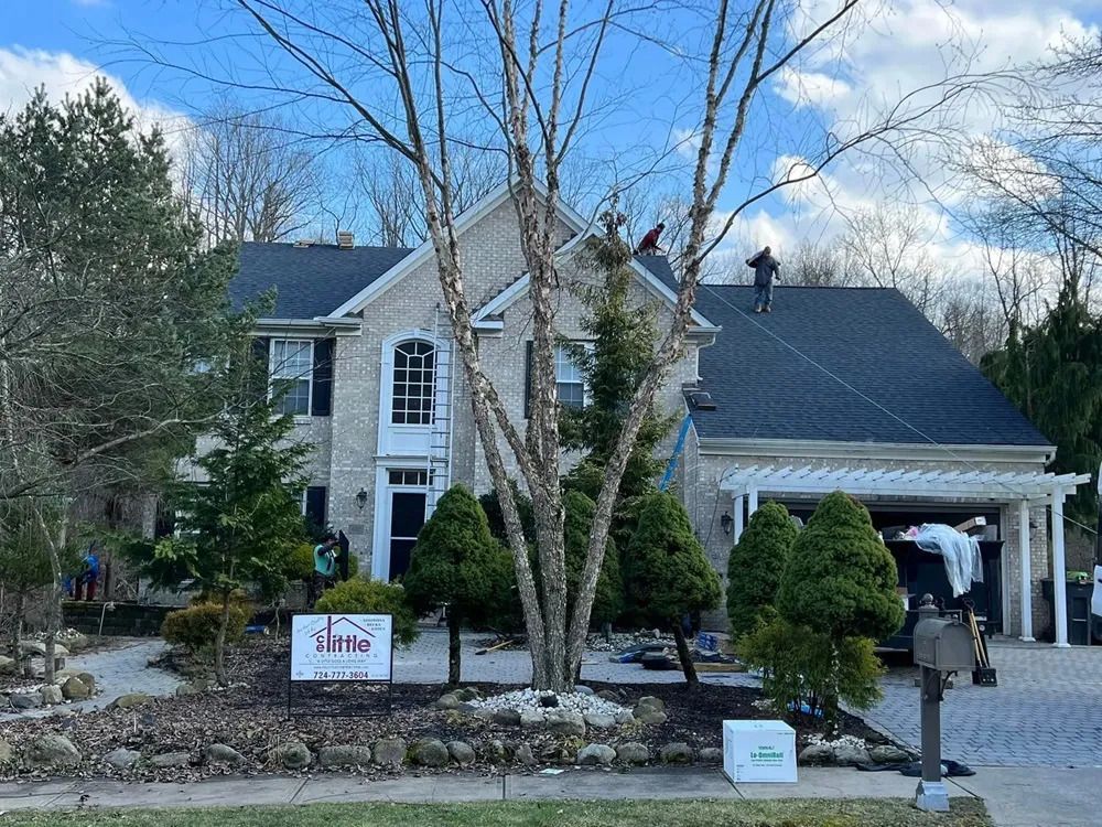 A man is working on the roof of a large house.
