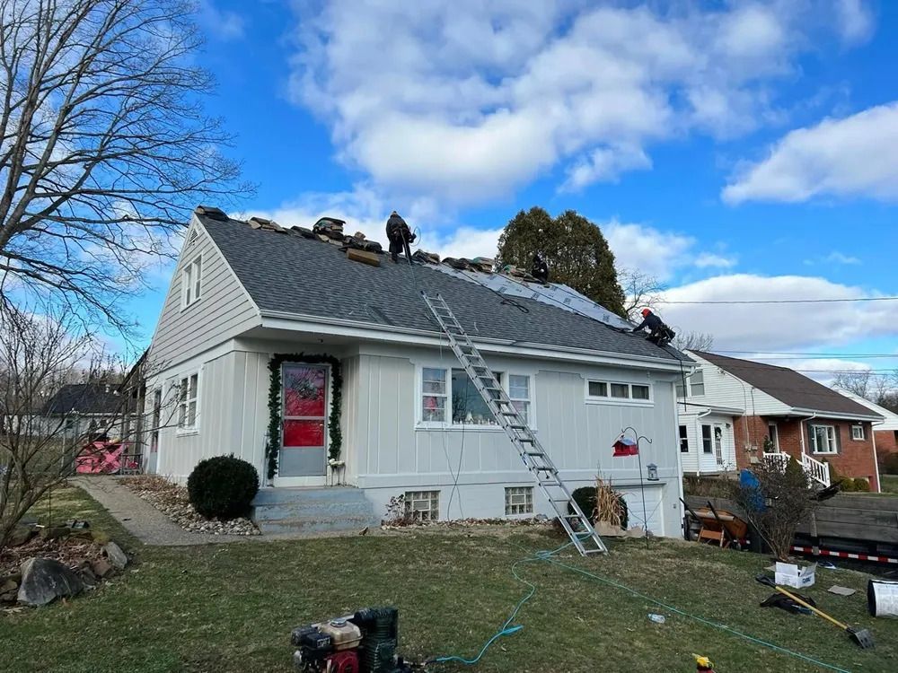 A white house is being remodeled with a roof being installed.