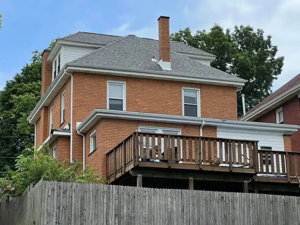 A brick house with a wooden deck and a chimney