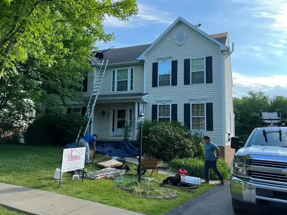 A man is standing in front of a house with a truck parked in front of it.