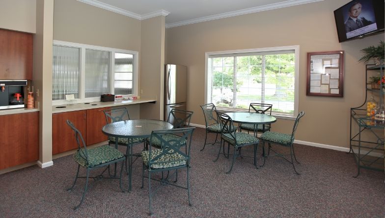 A room with tables and chairs and a television on the wall