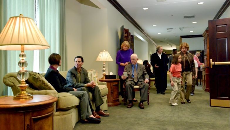 A group of people are standing and sitting in a hallway