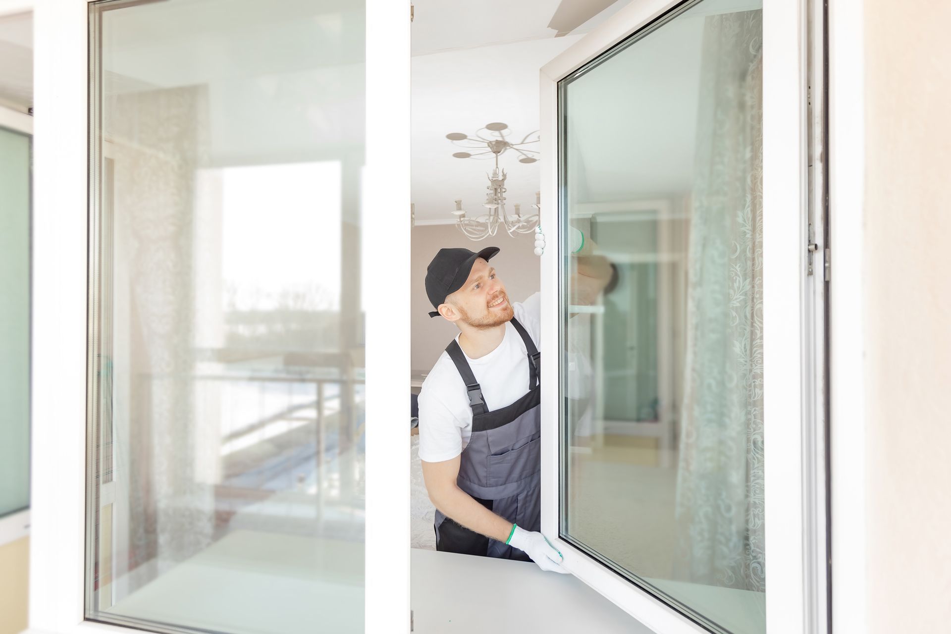 Worker installing a large glass window frame in a bright room