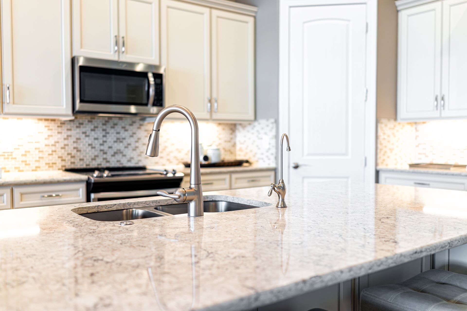 Bright modern kitchen with white cabinets, granite island, and stainless steel appliances