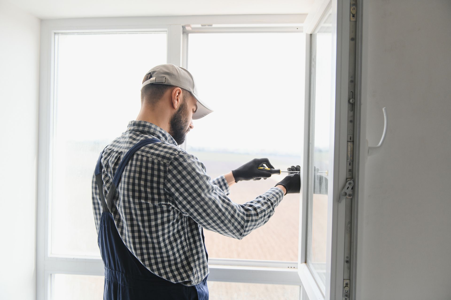 Worker using a power drill to install a window frame in a bright room