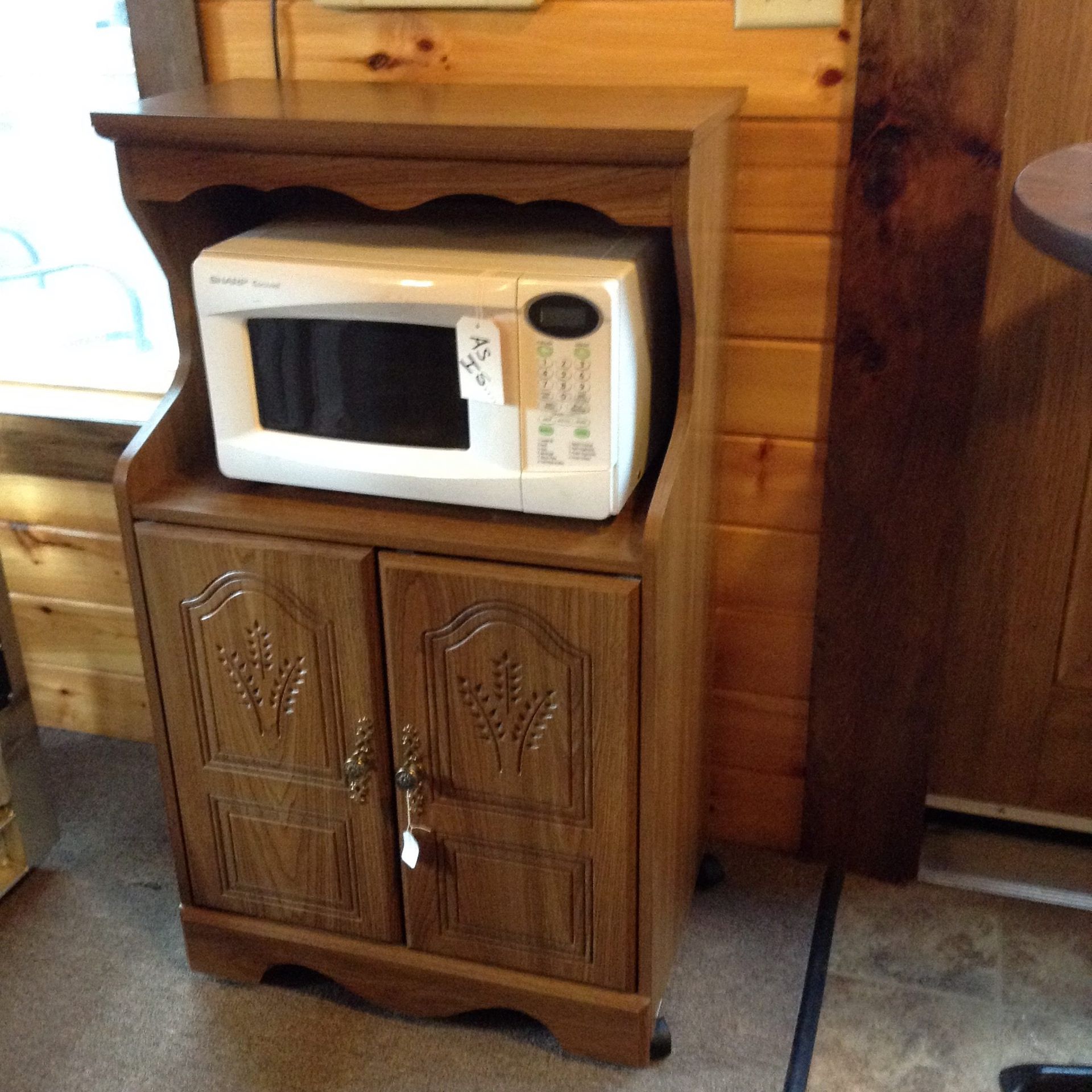 A microwave sits on top of a wooden cabinet