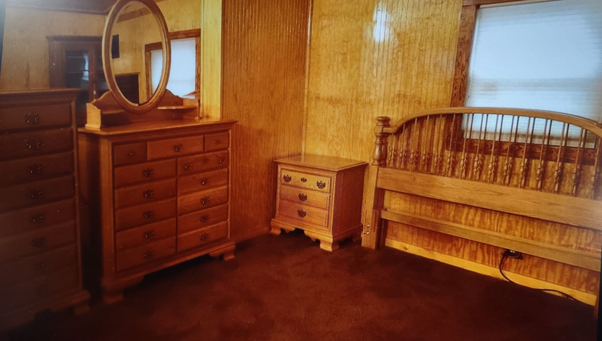 A bedroom with a bed , dresser , nightstand and mirror.