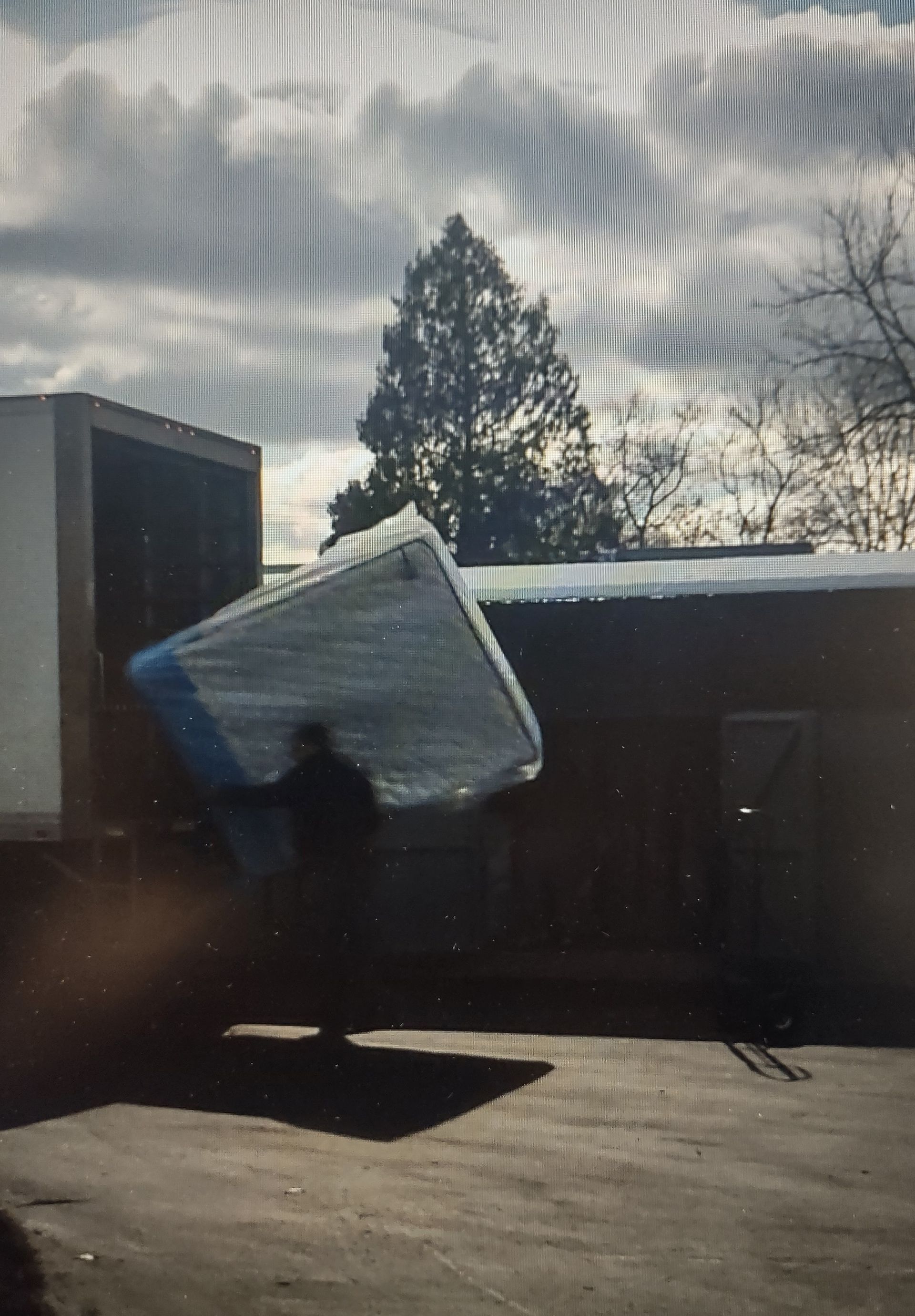 A man is carrying a mattress into a truck.